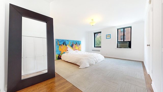 bedroom with crown molding, cooling unit, wood finished floors, and baseboards