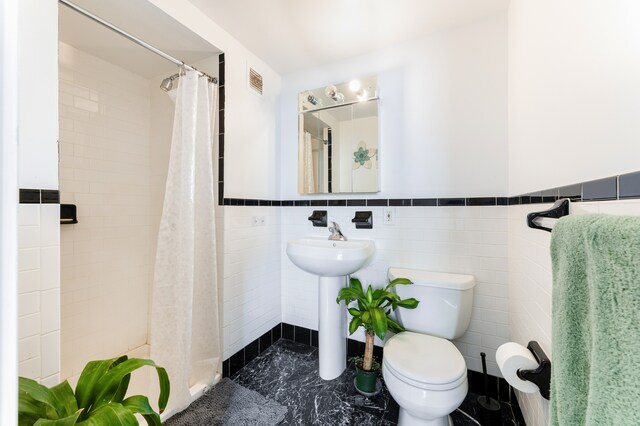 1831 Madison Ave Unit 9-F, New York City, NY 10035 - bathroom featuring a shower stall, toilet, tile walls, a wainscoted wall, and a sink