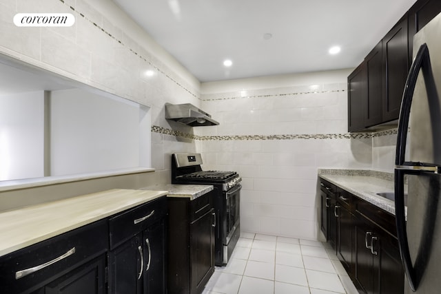 kitchen with light tile patterned floors, tile walls, gas stove, and black fridge