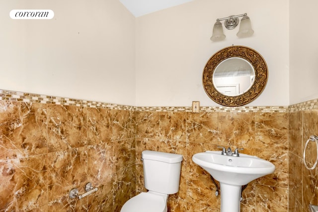 bathroom with toilet and tile walls