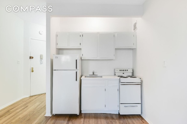 kitchen with white cabinetry, sink, hardwood / wood-style floors, and white appliances