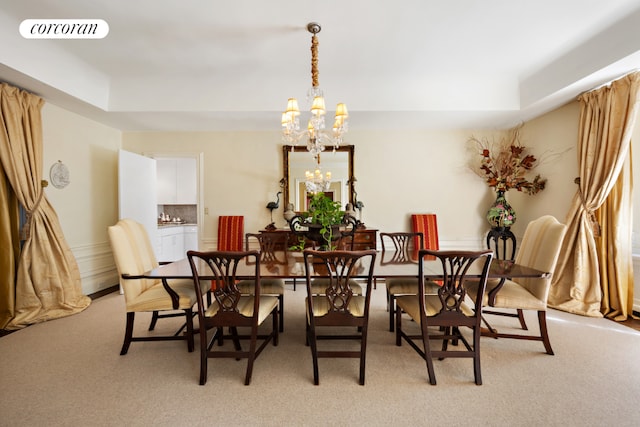 dining space with light colored carpet, a raised ceiling, and a chandelier