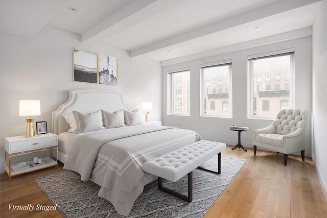 bedroom featuring multiple windows, beamed ceiling, and light wood finished floors