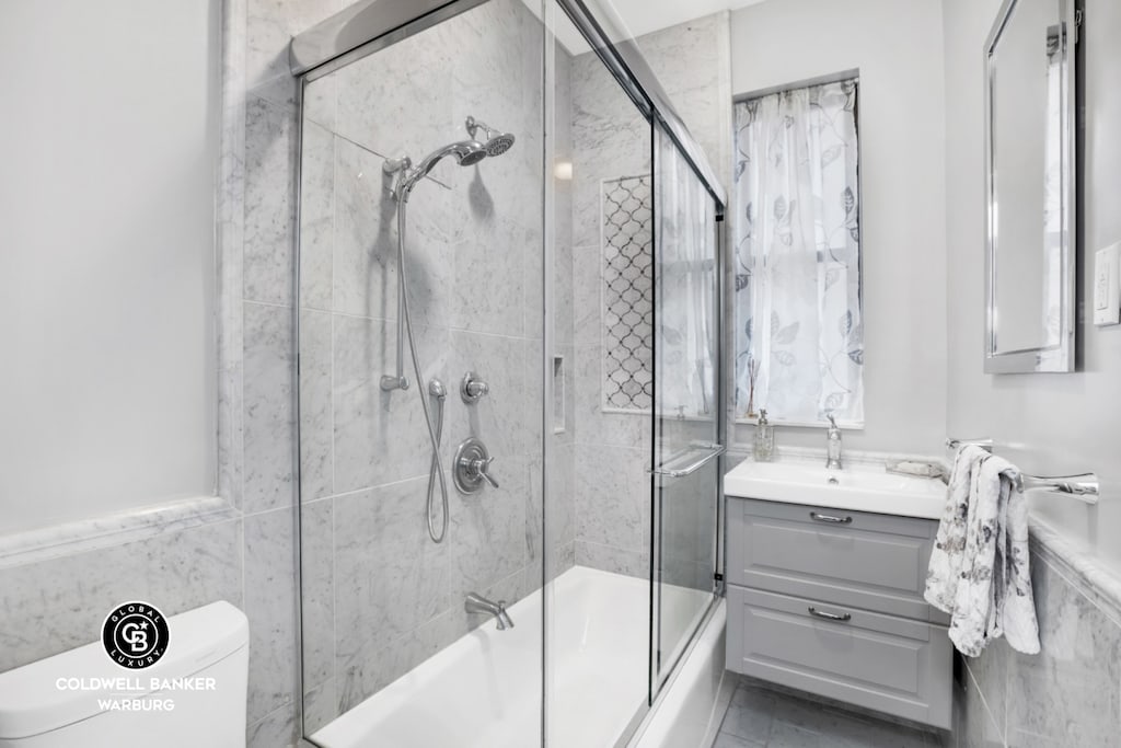 full bathroom with vanity, enclosed tub / shower combo, and toilet