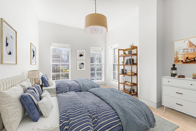 bedroom featuring a towering ceiling and light wood-style flooring