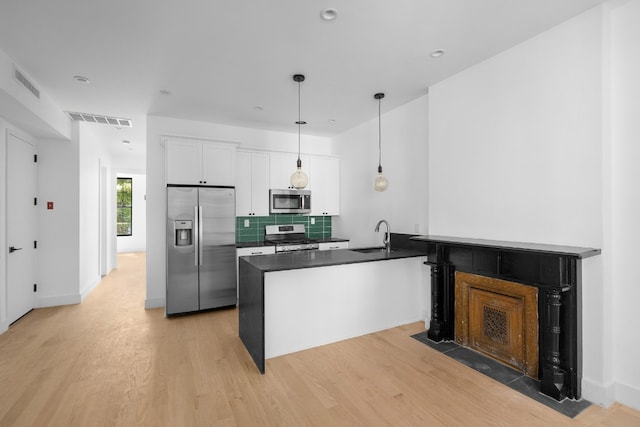 kitchen featuring tasteful backsplash, stainless steel appliances, hanging light fixtures, and white cabinets