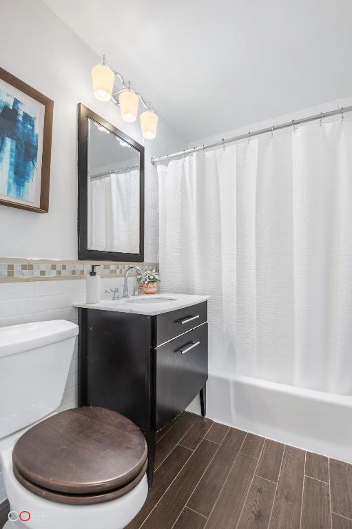 bathroom with vanity, tile walls, and toilet