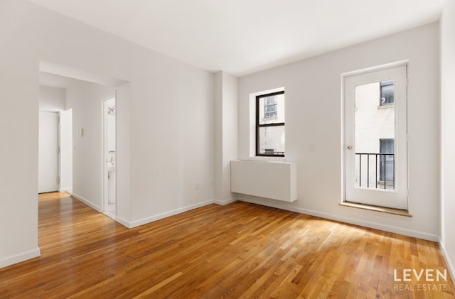 unfurnished room with baseboards and light wood-style floors