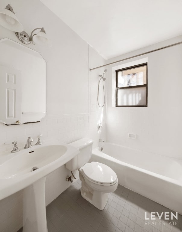 bathroom with shower / bathtub combination, tile patterned floors, toilet, and tile walls