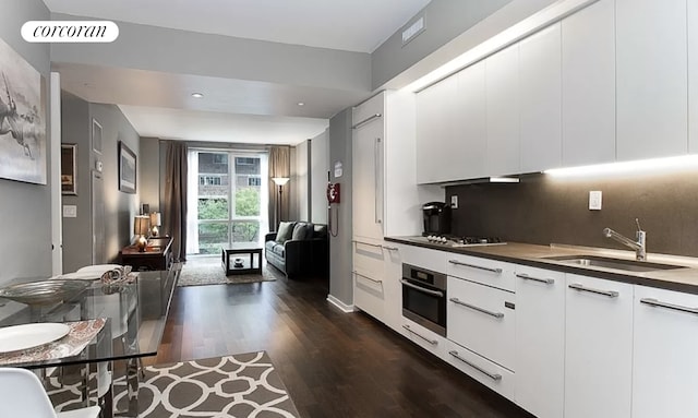 kitchen featuring dark wood finished floors, stainless steel appliances, visible vents, decorative backsplash, and a sink