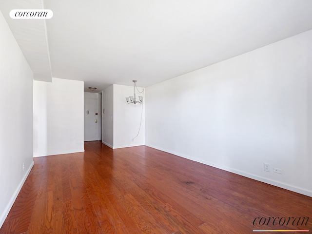 unfurnished room with baseboards, visible vents, a chandelier, and wood finished floors