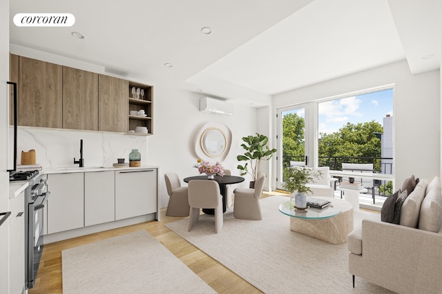 living room featuring sink, light hardwood / wood-style floors, and a wall unit AC