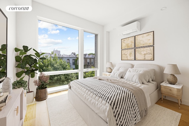 bedroom with light hardwood / wood-style floors and a wall unit AC