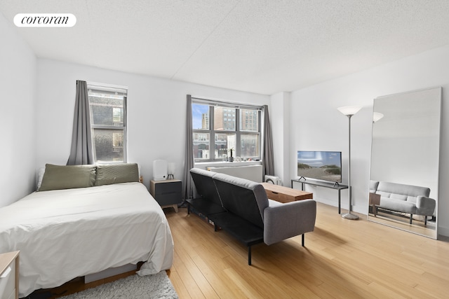 bedroom featuring hardwood / wood-style flooring, multiple windows, and a textured ceiling