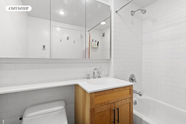 full bathroom with toilet, tile walls, vanity, tiled shower / bath combo, and decorative backsplash