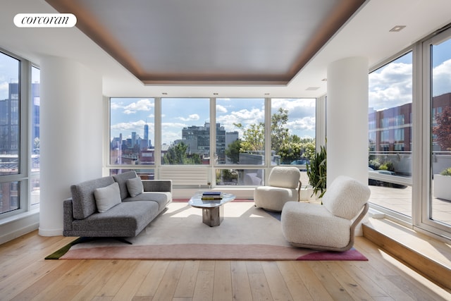 sunroom with a view of city, visible vents, a raised ceiling, and a wealth of natural light