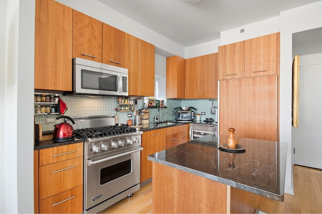 kitchen featuring a kitchen island, appliances with stainless steel finishes, backsplash, dark stone countertops, and modern cabinets