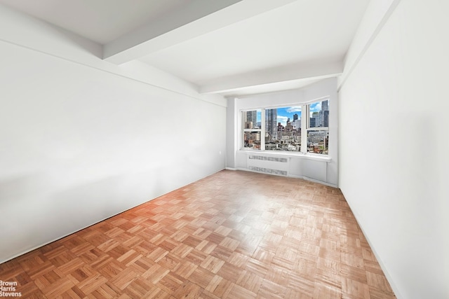 spare room featuring beamed ceiling, light parquet flooring, and radiator