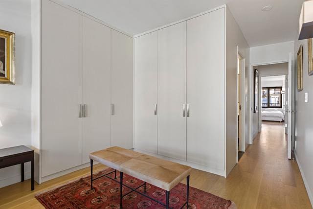 kitchen featuring white cabinetry, sink, stainless steel appliances, wall chimney range hood, and light wood-type flooring