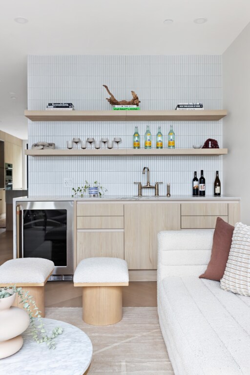 bar featuring beverage cooler, light brown cabinetry, and sink