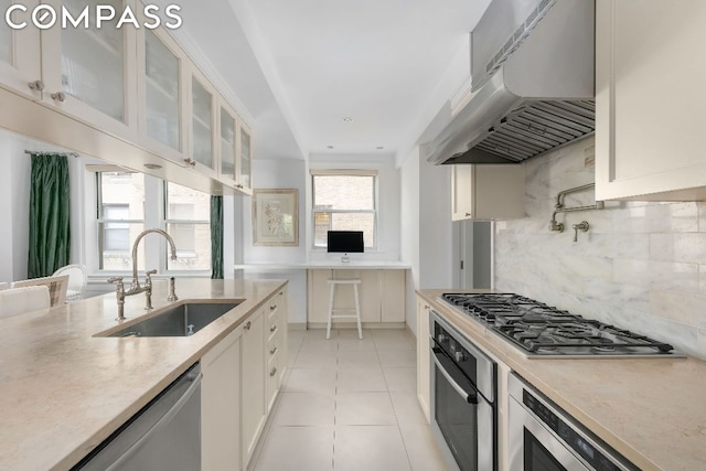 kitchen featuring tasteful backsplash, exhaust hood, sink, stainless steel appliances, and light tile patterned floors