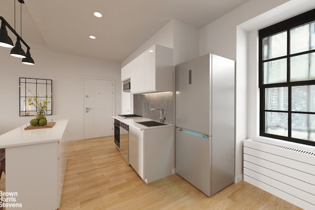 35 W 9th St Unit 1B, New York City, NY 10011 - kitchen with appliances with stainless steel finishes, a sink, radiator heating unit, white cabinets, and light wood-type flooring