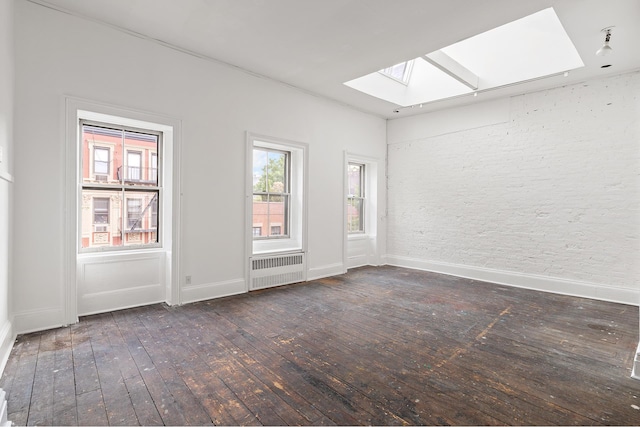 spare room with a wealth of natural light, a skylight, radiator heating unit, and hardwood / wood-style floors