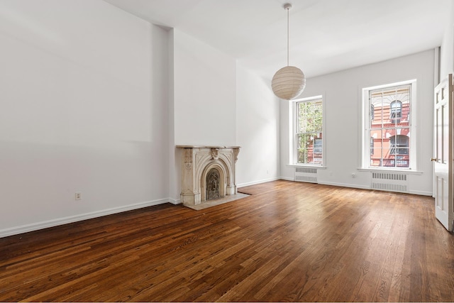 unfurnished living room featuring dark wood-type flooring, radiator heating unit, baseboards, and a fireplace with flush hearth