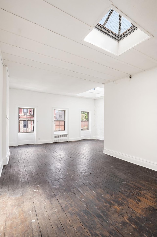 spare room featuring dark wood finished floors, radiator heating unit, and baseboards