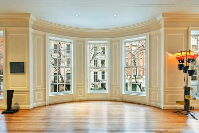 doorway with ornamental molding, a decorative wall, and wood finished floors