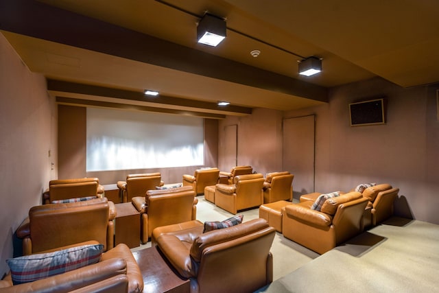 home theater room with beamed ceiling and light colored carpet