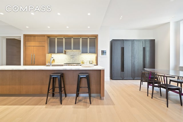 kitchen with a breakfast bar, light countertops, a sink, paneled fridge, and paneled refrigerator