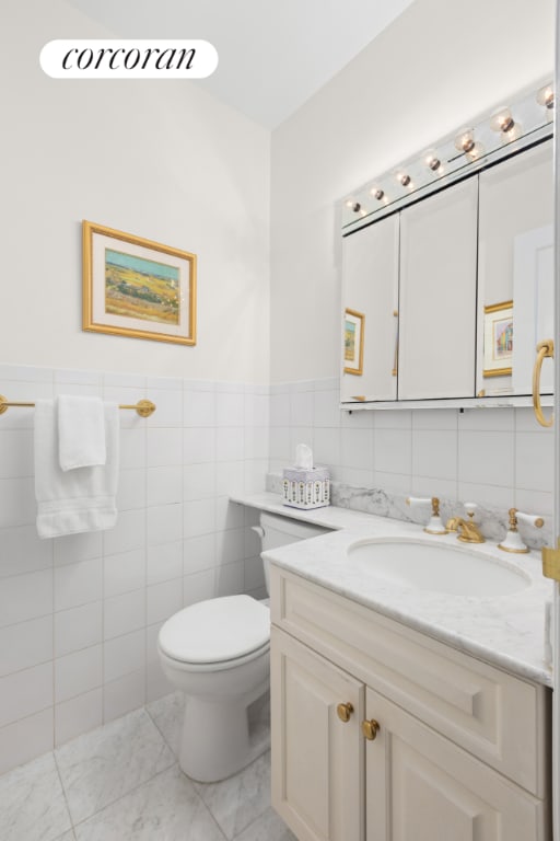 bathroom with toilet, tile walls, tile patterned floors, and vanity