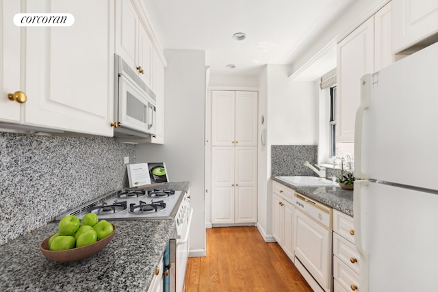 kitchen with light wood-type flooring, sink, white appliances, and white cabinetry