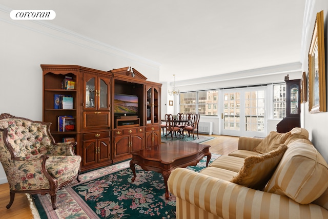 living room with crown molding, a notable chandelier, and light wood-type flooring