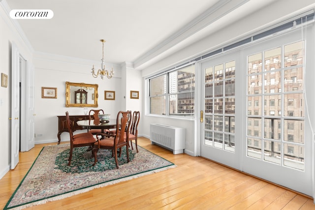 dining area featuring radiator, ornamental molding, light hardwood / wood-style flooring, and a notable chandelier