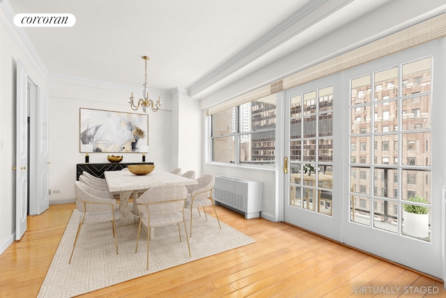 dining space with hardwood / wood-style floors, radiator, ornamental molding, and an inviting chandelier