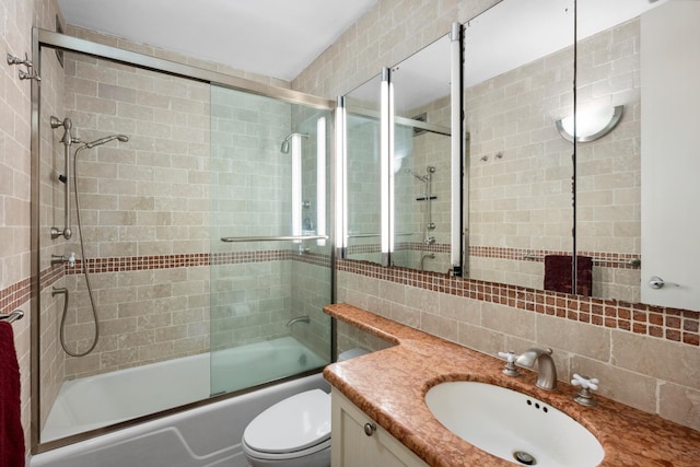 full bath with backsplash, bath / shower combo with glass door, vanity, and toilet