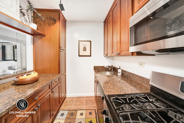 kitchen with appliances with stainless steel finishes, sink, and dark stone counters