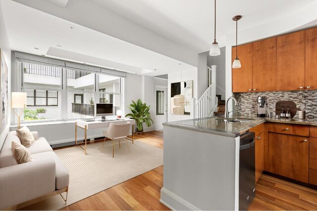 kitchen with sink, light hardwood / wood-style flooring, black dishwasher, kitchen peninsula, and decorative backsplash