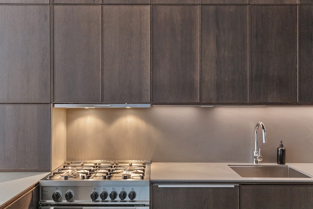 kitchen with extractor fan, sink, high end stainless steel range, and dark brown cabinetry