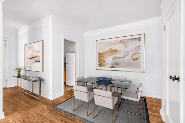 dining room with hardwood / wood-style flooring and crown molding