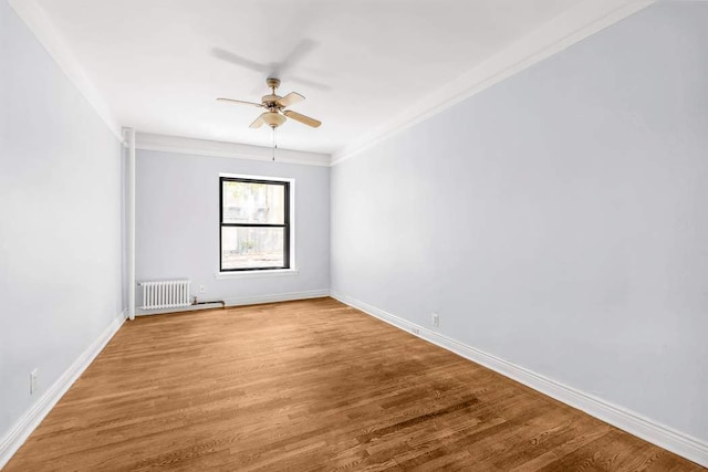 empty room featuring hardwood / wood-style flooring, ceiling fan, radiator heating unit, and crown molding