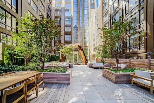 view of home's community featuring outdoor lounge area, outdoor dining space, a wooden deck, and a garden