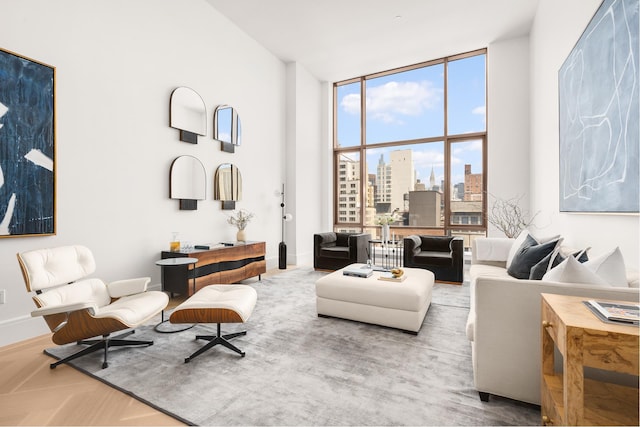 living area with baseboards, a city view, and a high ceiling