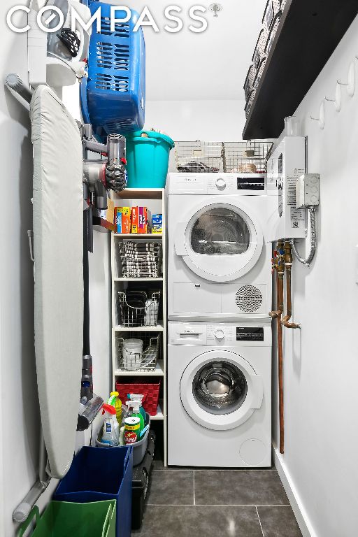 clothes washing area with stacked washer / dryer and dark tile patterned floors