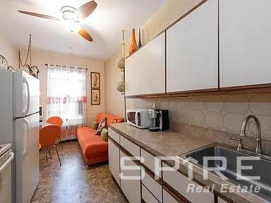 kitchen with backsplash, sink, white fridge, and white cabinets