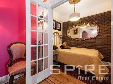 bedroom with brick wall and hardwood / wood-style floors