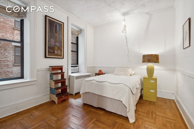 bedroom with baseboards, a textured ceiling, radiator heating unit, and crown molding