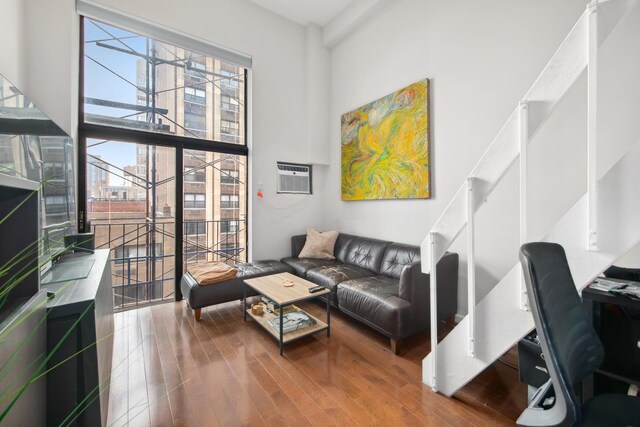 living room featuring a wall mounted air conditioner, a high ceiling, and hardwood / wood-style flooring